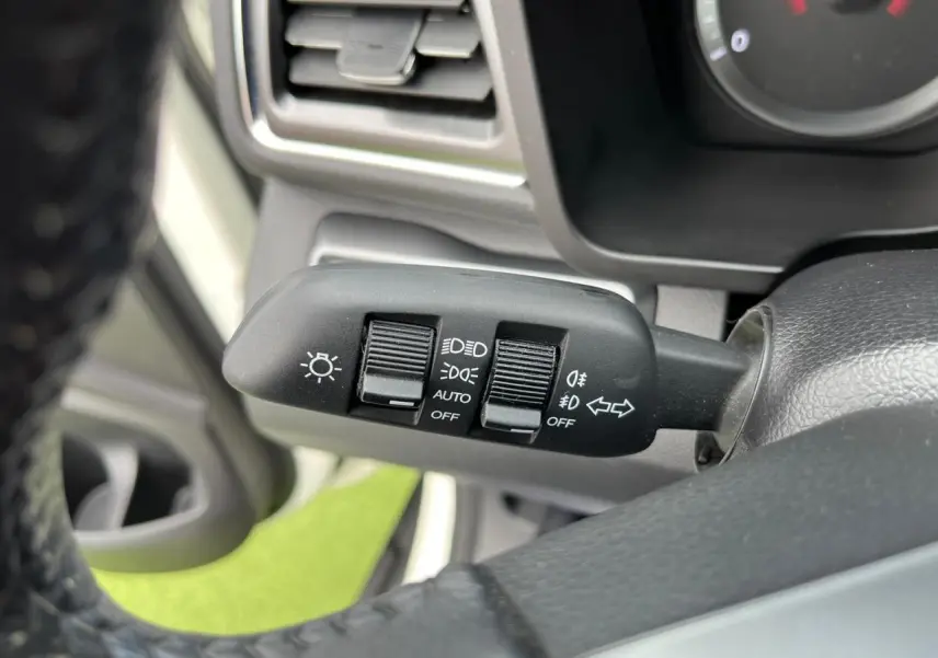 Gros plan sur la commande des phares et clignotants à gauche du volant d’un SsangYong Tivoli blanc de 2021.