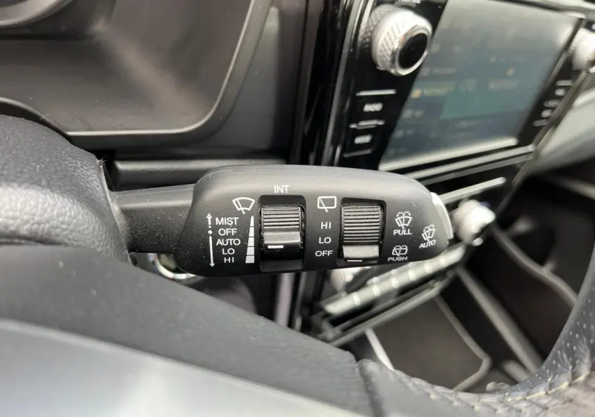 Gros plan sur la commande d’essuie-glace à gauche du volant dans l’habitacle noir du SsangYong Tivoli blanc 2021.