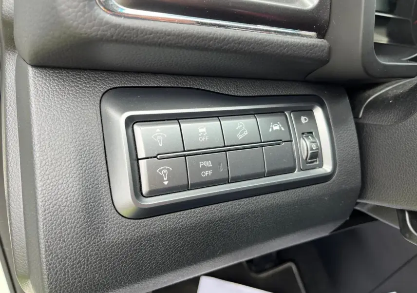 Gros plan sur les commandes d'assistance et réglage des phares côté gauche du tableau de bord du SsangYong Tivoli blanc 2021.