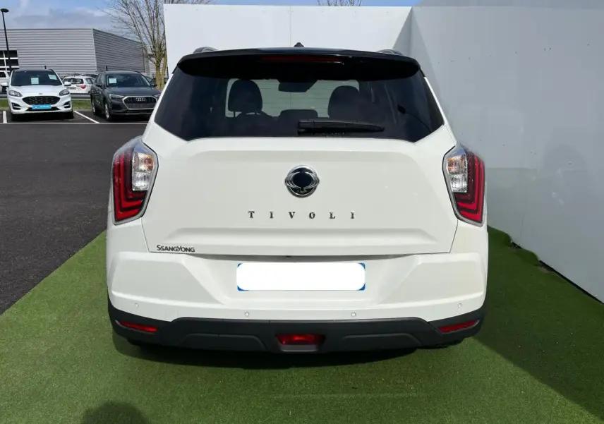Vue arrière d'un SsangYong Tivoli blanc 2021 avec feux LED et vitre arrière surteintée sur fond extérieur.