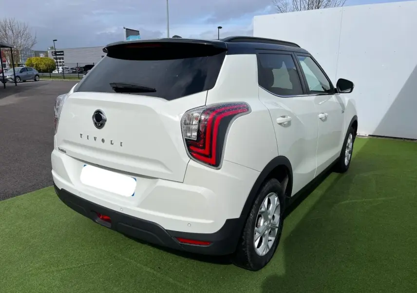 Vue 3/4 arrière droit du SsangYong Tivoli blanc avec toit noir, feux arrière LED et jantes alliage 16 pouces.
