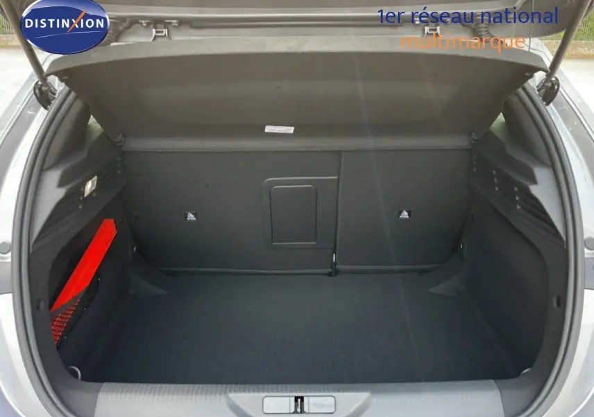 Coffre ouvert d’une Peugeot 308 gris Artense métal, vue arrière montrant l’espace de chargement vide et un triangle de signalisation rouge.