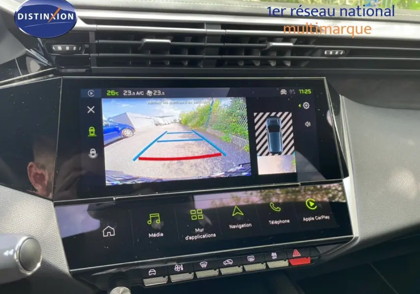 Vue rapprochée de l’écran tactile central de la Peugeot 308 gris Artense, affichant la caméra de recul et les options multimédia.