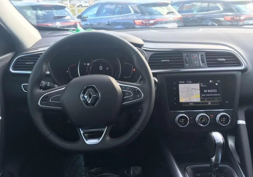 Vue intérieure frontale du tableau de bord du Renault Kadjar gris titanium, avec volant multifonction et écran tactile central allumé.