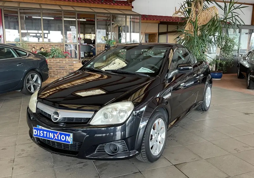 Opel Tigra Twintop noir vue 3/4 avant droit dans un showroom avec plaque Distinxion visible