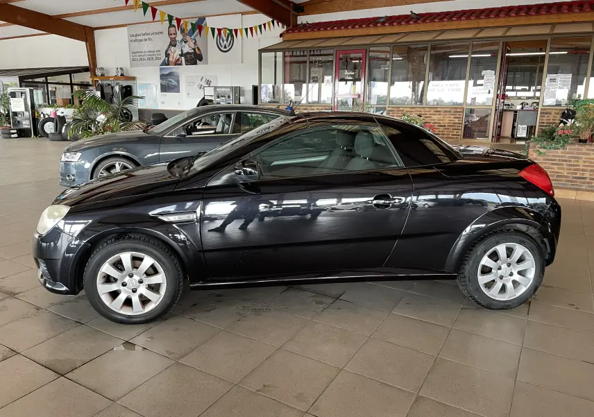 Opel Tigra Twintop noir vue de profil côté gauche, coupé compact avec toit rigide rétractable en showroom.