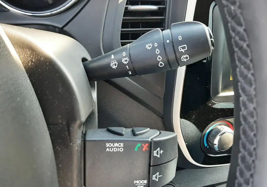 Gros plan sur la commande des phares et clignotants à gauche du volant dans l'habitacle gris noir du Renault Captur 2019.