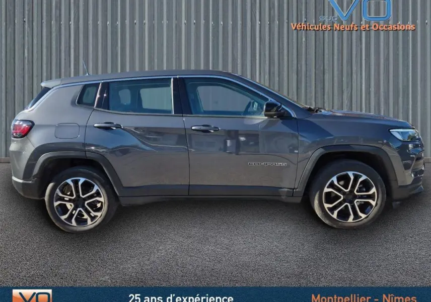 Vue de profil côté gauche d'un Jeep Compass gris 2024 avec jantes alliage 18 pouces sur fond urbain.