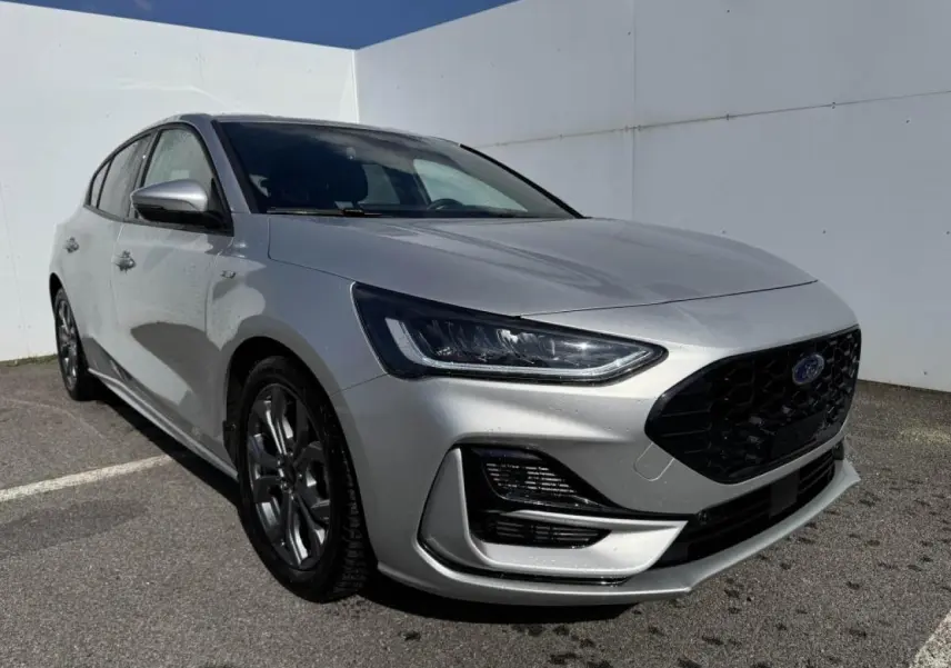 Ford Focus IV ST-Line X gris Moondust métal vue 3/4 avant avec calandre noire et jantes alliage 17 pouces.