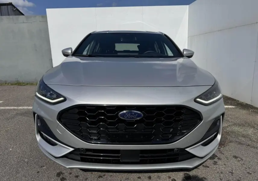 Vue frontale d'une Ford Focus IV ST-Line gris Moondust Metal avec calandre noire hexagonale et phares LED.