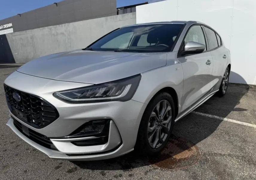 Ford Focus IV ST-Line X gris Moondust métal vue 3/4 avant avec calandre noire et jantes alliage 17 pouces.