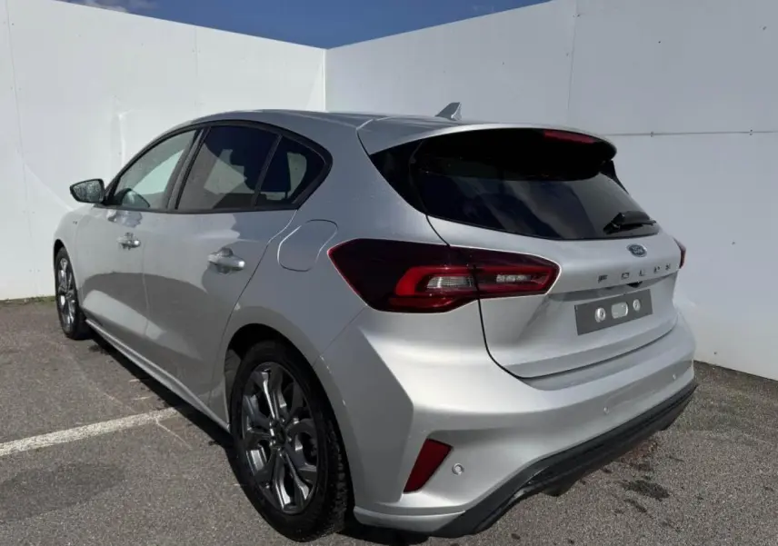 Ford Focus IV ST-Line X gris Moondust métal vue 3/4 arrière droit avec jantes alliage 17'' et becquet carrosserie