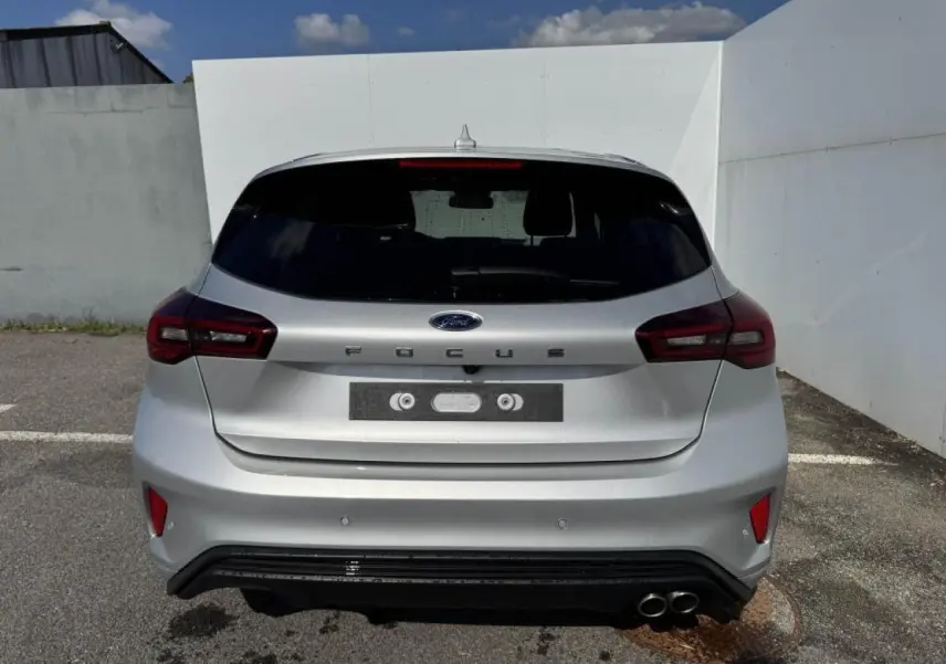 Vue arrière d'une Ford Focus IV gris Moondust Metal avec double sortie d'échappement et feux LED distinctifs.