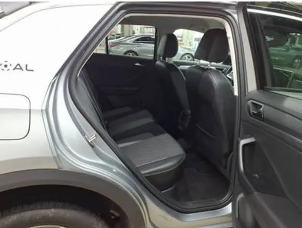 Vue intérieure arrière côté gauche du Volkswagen T-Roc gris clair 2025, montrant les sièges arrière en tissu noir.