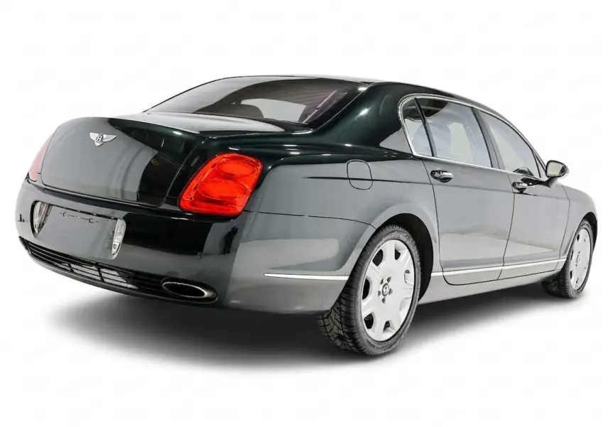 Vue 3/4 arrière droite d'une Bentley Continental Flying Spur vert foncé avec feux arrière rouges et jantes argentées.