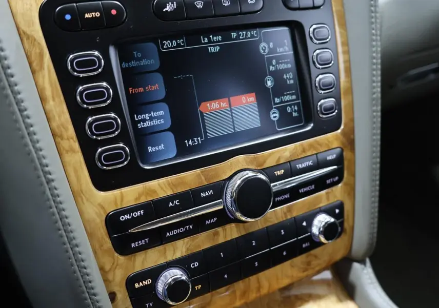 Gros plan sur la console centrale en bois clair de la Bentley Continental Flying Spur 2006, affichage numérique et commandes audio.