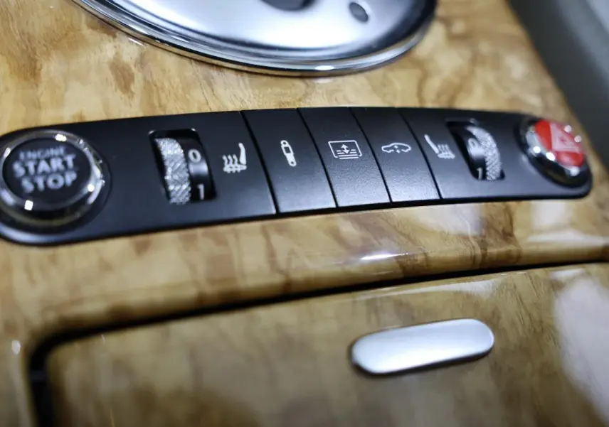 Gros plan sur la console en bois clair de la Bentley Continental Flying Spur 2006, montrant les boutons de démarrage et réglages sièges.