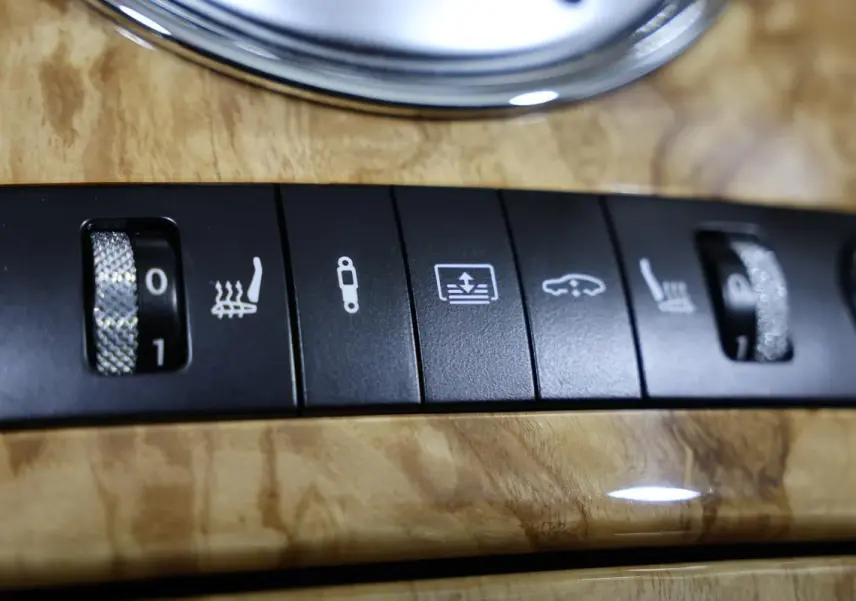 Gros plan sur les commandes de réglage des sièges chauffants et suspension sur bois clair intérieur d’une Bentley Continental Flying Spur 2006.