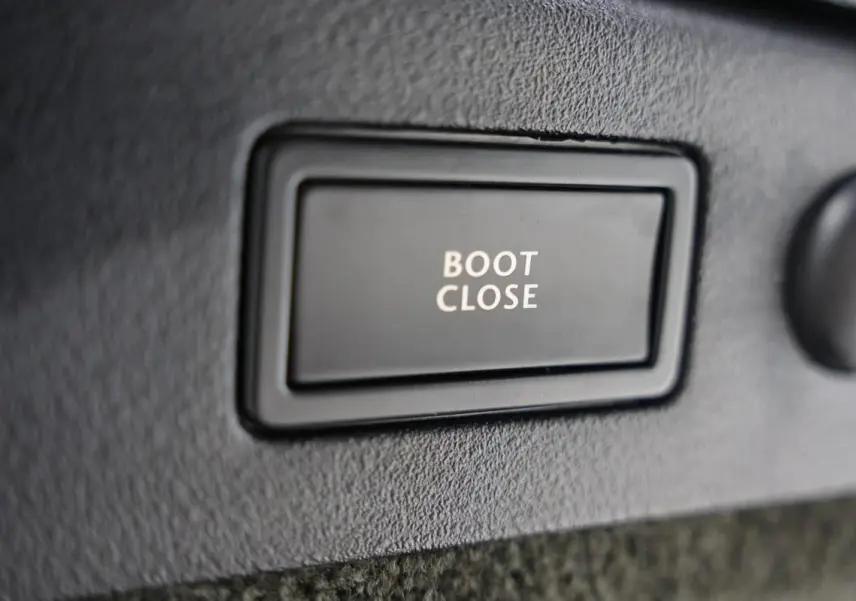 Gros plan sur le bouton "Boot Close" noir dans le coffre d'une Bentley Continental Flying Spur vert foncé de 2006.