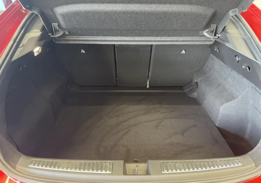 Coffre ouvert vu de l'arrière d'une Renault Rafale rouge avec intérieur noir et banquette rabattue partiellement.