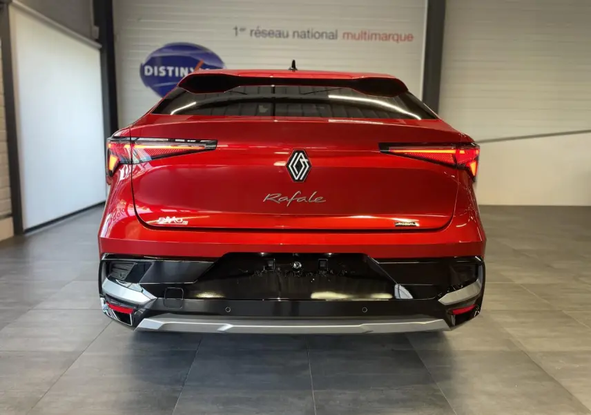 Vue arrière d'une Renault Rafale rouge à toit noir, avec feux LED fins et logo central dans un showroom.