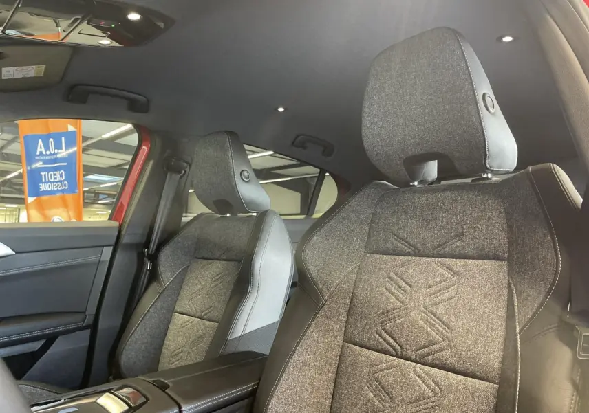 Vue intérieure côté avant droit de la Renault Rafale 2025, sièges sport gris avec motifs embossés et accoudoir central noir.