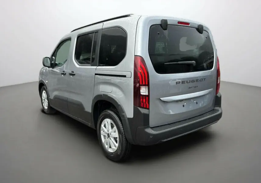 Vue 3/4 arrière droit du Peugeot Rifter gris Artense avec vitres surteintées et grille de séparation visible dans le coffre.