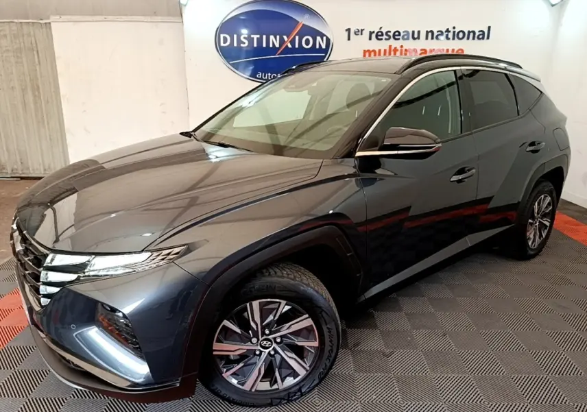 Vue 3/4 avant droit du Hyundai Tucson 1.6 Hybrid 230 Creative gris foncé, avec jantes alliage et vitres teintées.