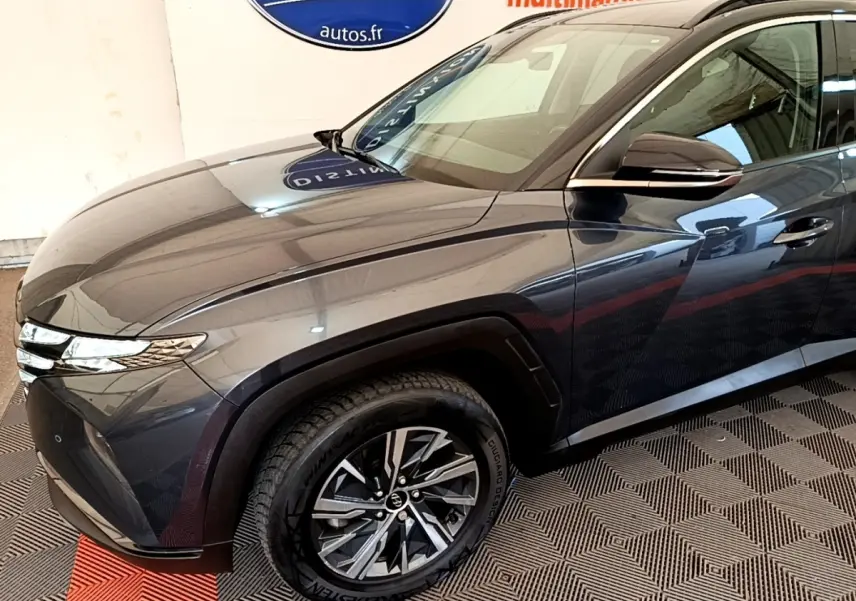 Vue 3/4 avant droit du Hyundai Tucson gris foncé 2022 avec jantes alliage et phares LED fins.