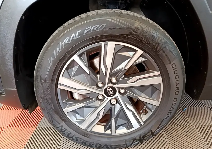 Gros plan sur la roue avant droite du Hyundai Tucson gris foncé, avec jante alu au design géométrique moderne.