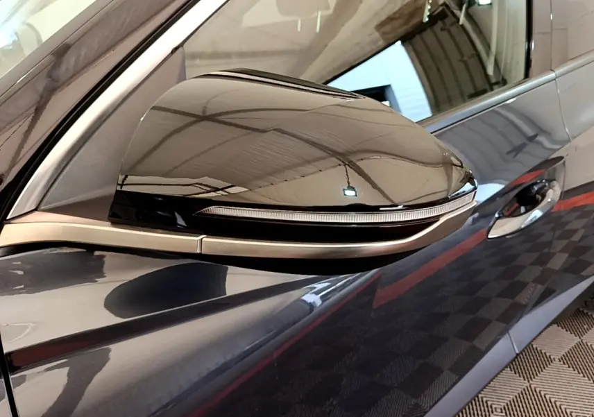 Gros plan sur le rétroviseur côté gauche gris foncé du Hyundai Tucson 1.6 Hybrid 230 Creative avec clignotant intégré.