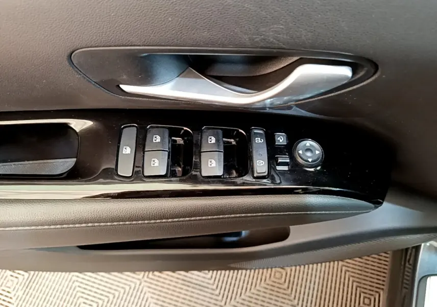 Gros plan sur la commande des vitres et rétroviseurs côté conducteur d’un Hyundai Tucson gris foncé 2022.