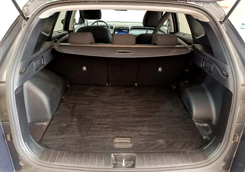 Coffre ouvert d’un Hyundai Tucson gris foncé, vue arrière montrant l’espace de chargement et la tablette cache-bagages.