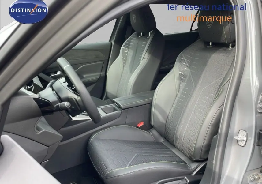 Vue intérieure côté conducteur de la Peugeot 308 gris selenium, mettant en valeur les sièges en tissu et cuir avec surpiqûres vertes.