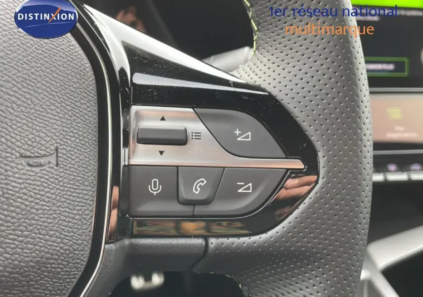 Gros plan sur les commandes gauche du volant perforé d'une Peugeot 308 gris selenium, avec boutons audio et appel.