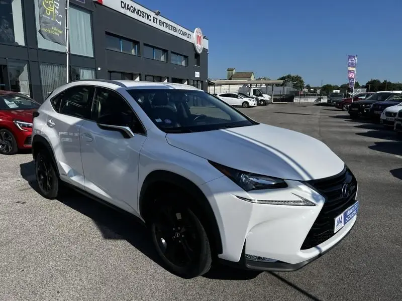 Lexus NX 300H blanc nacré en 3/4 avant droit, avec jantes noires et calandre imposante, stationné devant un garage.
