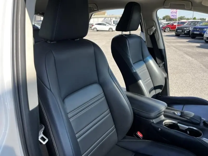 Gros plan sur les sièges avant en cuir noir du Lexus NX 300H blanc nacré, avec console centrale et porte-gobelets visibles.