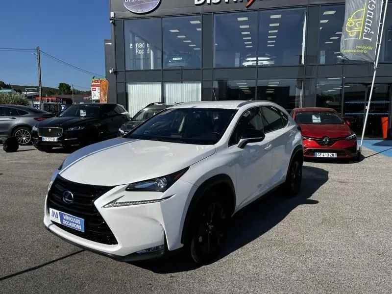 Lexus NX 300H blanc nacré en 3/4 avant droit, avec calandre noire et jantes foncées, stationné devant un bâtiment vitré.