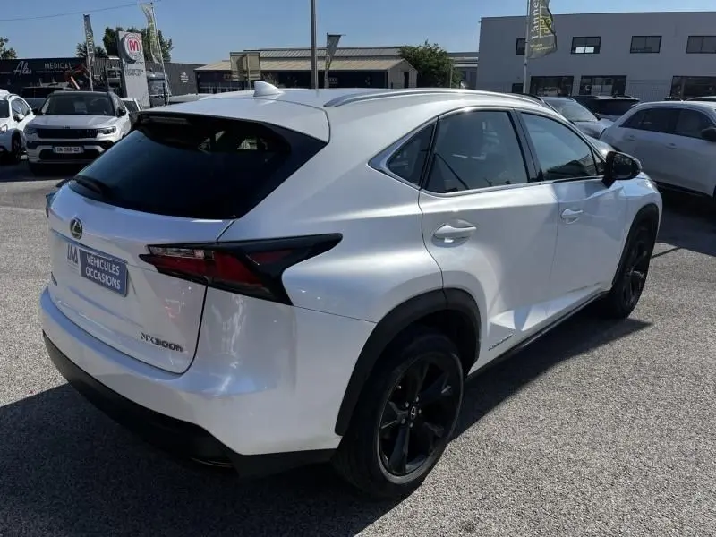 Vue 3/4 arrière droite d'un Lexus NX 300H blanc nacré avec jantes noires et vitres teintées, stationné en extérieur.