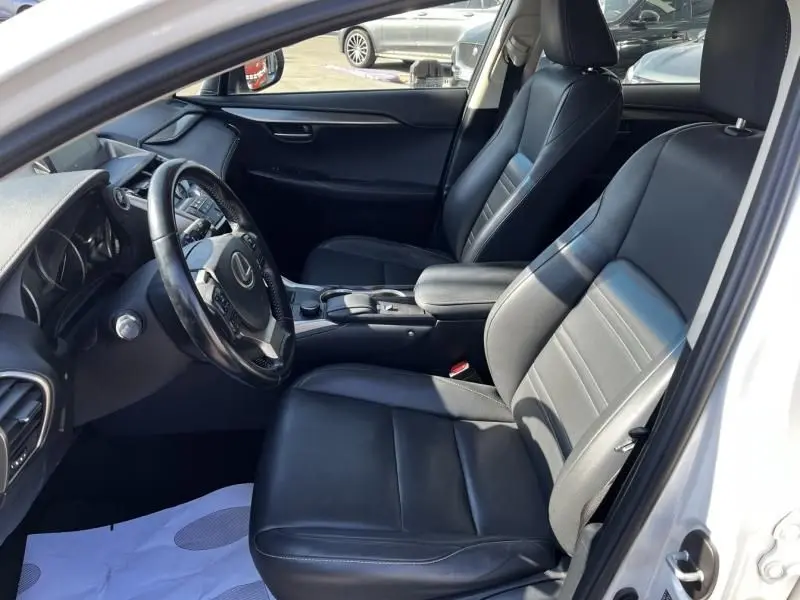 Vue intérieure côté conducteur du Lexus NX 300H blanc nacré, sièges en cuir noir et tableau de bord moderne.