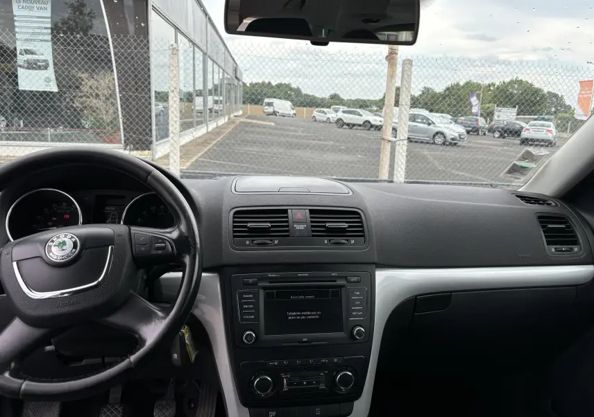 Vue intérieure frontale du tableau de bord gris et noir d'une Skoda Yeti Ambition 2012 avec volant à gauche et écran central éteint.