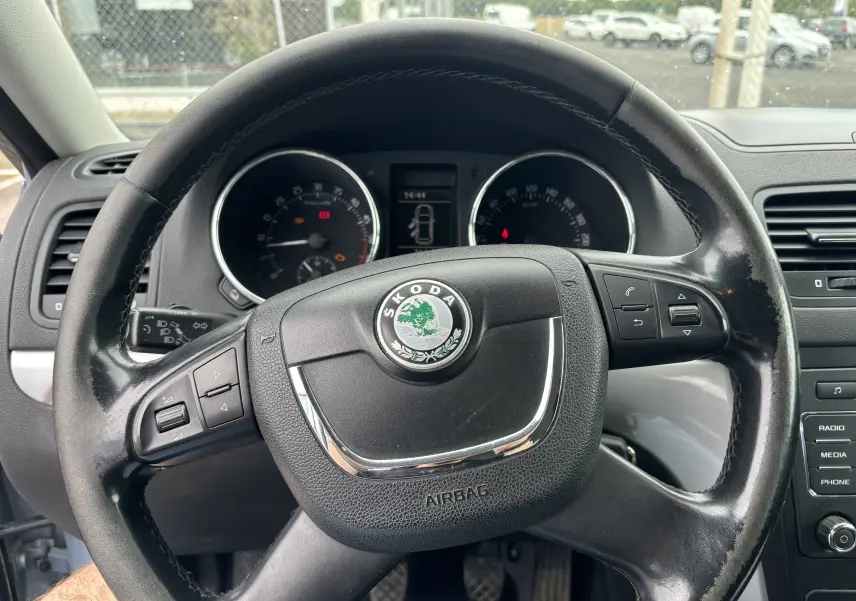 Vue rapprochée du volant noir de la Skoda Yeti Ambition 2012 avec commandes intégrées et tableau de bord visible.