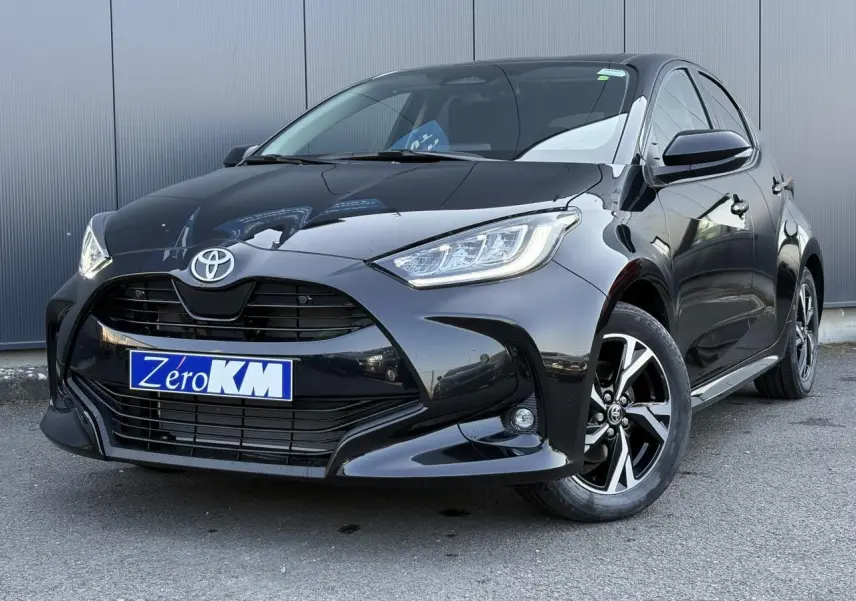 Toyota Yaris Hybride 2025 noir intense vue 3/4 avant droit avec jantes alliage et phares LED allumés.
