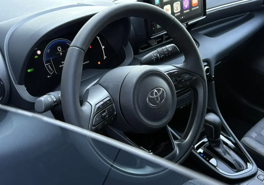 Vue rapprochée du volant cuir et du tableau de bord numérique de la Toyota Yaris Hybride 2025 noir intense.