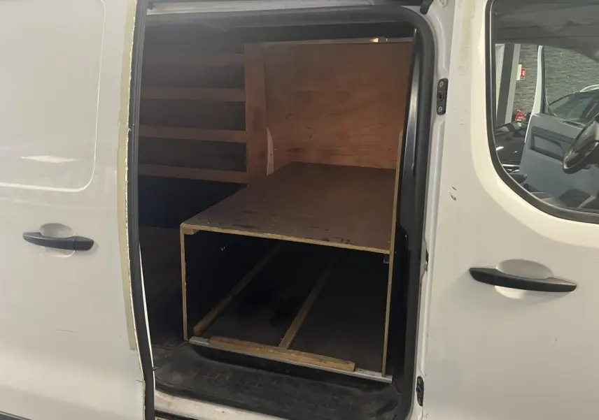 Vue intérieure côté droit du Peugeot Expert Fourgon blanc 2020 avec plancher bois antidérapant et cloison tôlée visible.