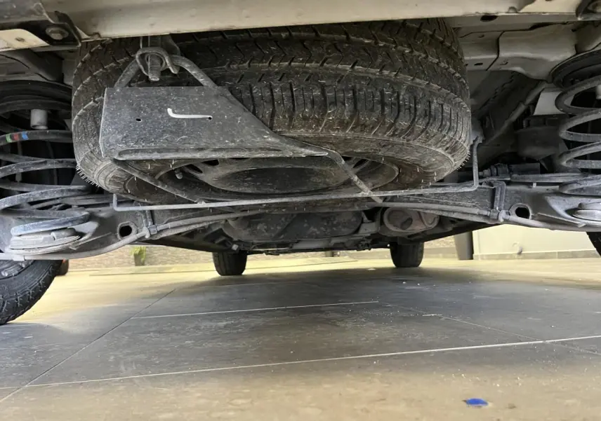 Vue en contre-plongée sous un Peugeot Expert Fourgon blanc, montrant la roue de secours et la suspension arrière.