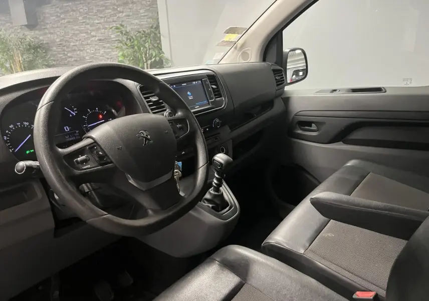 Vue intérieure côté conducteur du Peugeot Expert Fourgon 2020, volant multifonction et sièges tissu noir.
