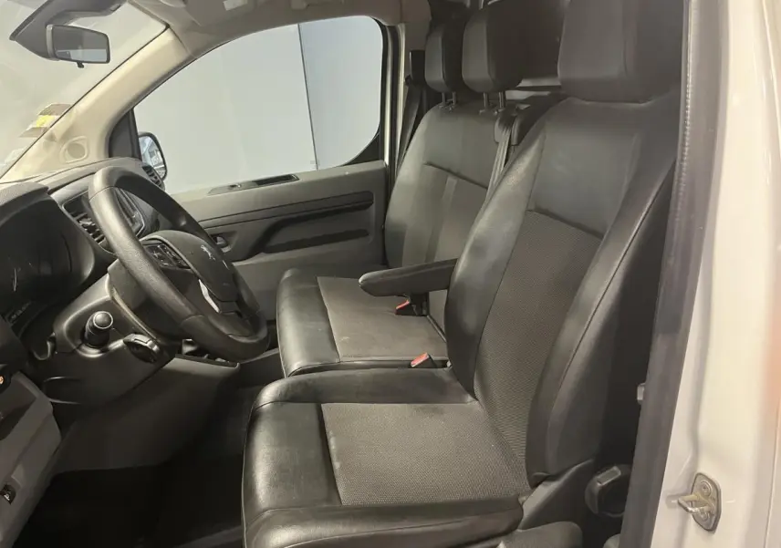 Vue intérieure côté conducteur du Peugeot Expert Fourgon blanc 2020, sièges en tissu et cuir noir avec accoudoir.