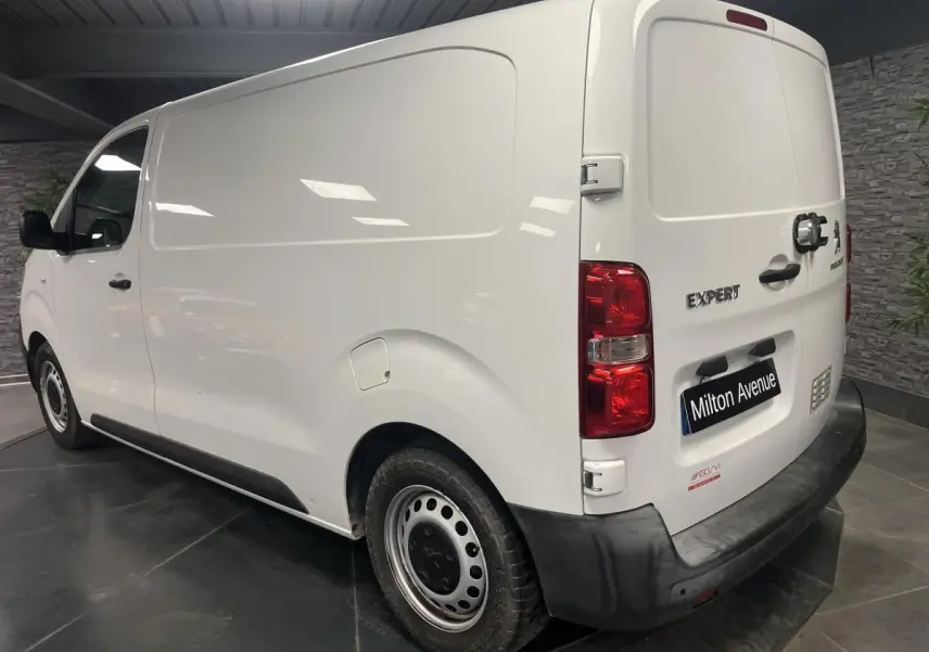 Vue 3/4 arrière droite d'un Peugeot Expert Fourgon blanc avec boucliers noirs et portes arrière tôlées ouvertes à 180°.