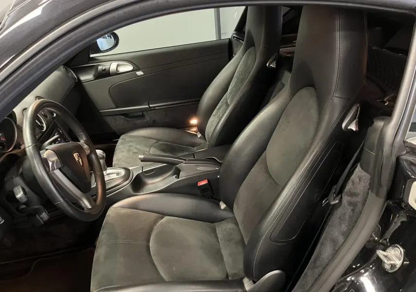 Intérieur noir de Porsche Cayman 987 vu côté gauche, avec sièges sport en cuir et alcantara, volant 3 branches.